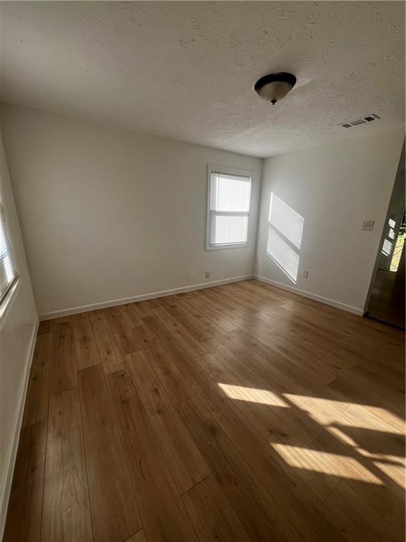 unfurnished room featuring hardwood / wood-style floors and a textured ceiling