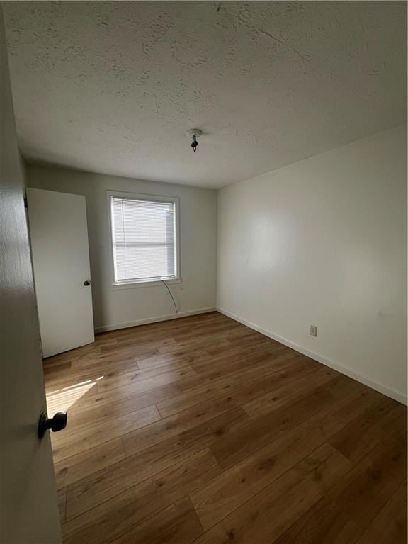 empty room with light hardwood / wood-style flooring and a textured ceiling