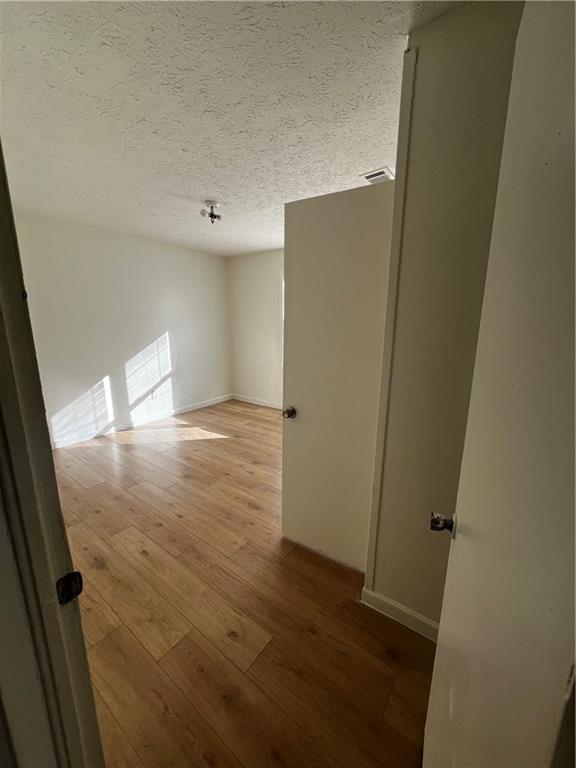 empty room with wood-type flooring and a textured ceiling