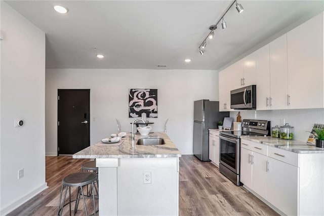 kitchen featuring a kitchen breakfast bar, appliances with stainless steel finishes, sink, white cabinetry, and an island with sink