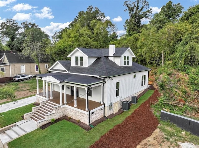 view of front of home featuring a porch, cooling unit, and a front yard