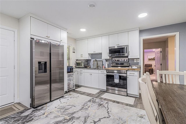 1549 Miller Valley Dr, Bethlehem, GA 30620 - kitchen with stainless steel appliances, a sink, white cabinets, light wood-type flooring, and recessed lighting