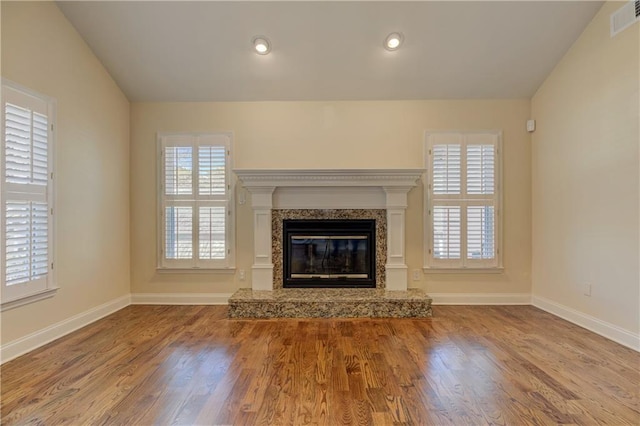 unfurnished living room featuring a high end fireplace, recessed lighting, baseboards, and wood finished floors