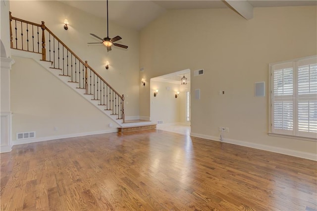 unfurnished living room with visible vents, wood finished floors, a ceiling fan, and stairway