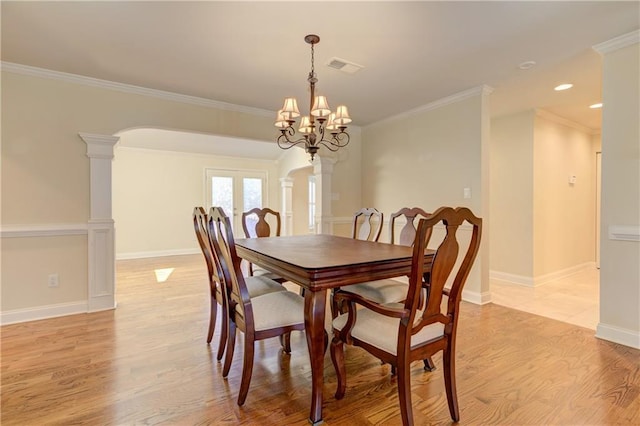 dining room with visible vents, light wood-type flooring, french doors, arched walkways, and ornate columns