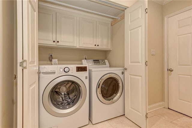 laundry room with washer and dryer, baseboards, cabinet space, and light tile patterned flooring