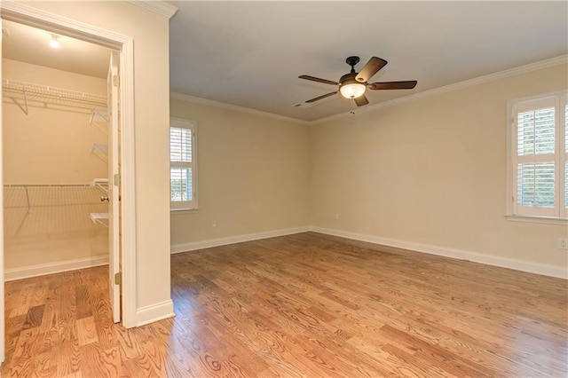 unfurnished bedroom with a spacious closet, light wood-type flooring, baseboards, and ornamental molding