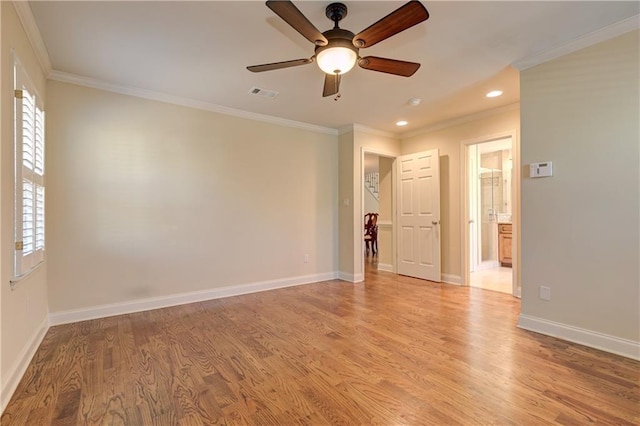 spare room with crown molding, plenty of natural light, visible vents, and light wood finished floors