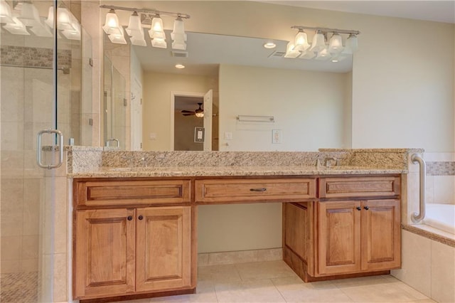 bathroom featuring tile patterned floors, a sink, tiled bath, a shower stall, and double vanity