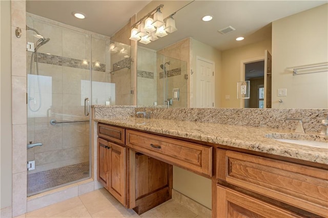 full bathroom featuring visible vents, double vanity, a stall shower, tile patterned floors, and a sink