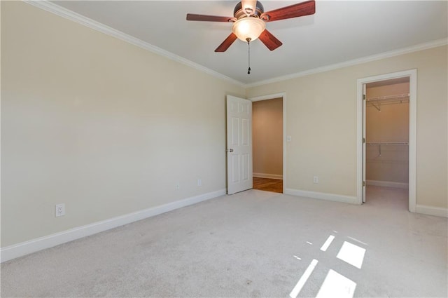 unfurnished bedroom with a walk in closet, carpet, crown molding, baseboards, and a closet