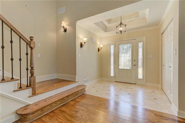 foyer featuring visible vents, a tray ceiling, and ornamental molding