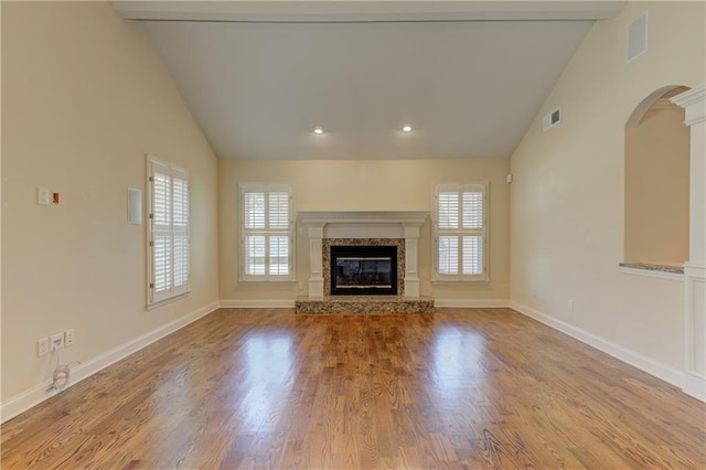 unfurnished living room with visible vents, wood finished floors, a healthy amount of sunlight, and a premium fireplace