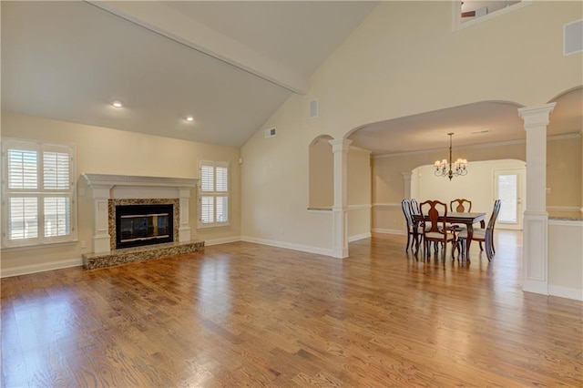 living room featuring decorative columns, a fireplace, light wood-type flooring, and plenty of natural light