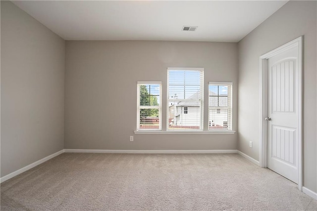 spare room featuring light carpet, healthy amount of natural light, and baseboards