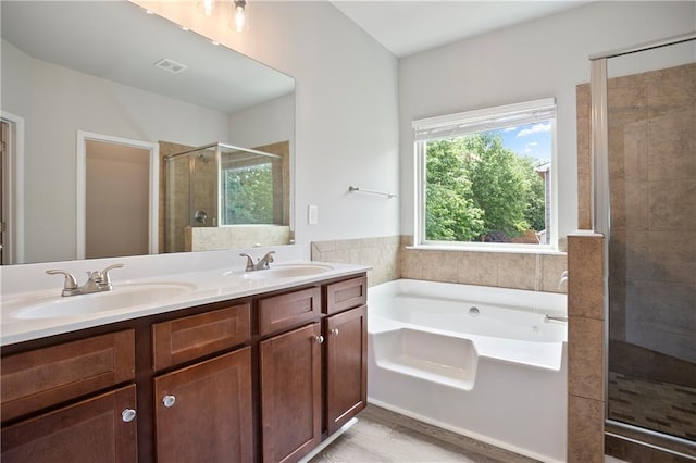 full bath featuring a stall shower, a garden tub, double vanity, and wood finished floors