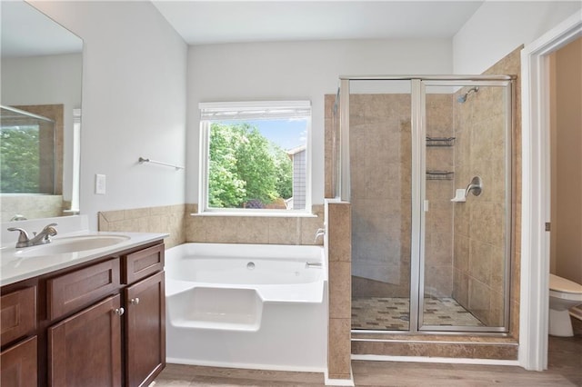 bathroom featuring a shower stall, toilet, a garden tub, vanity, and wood finished floors