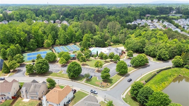 aerial perspective of suburban area featuring a heavily wooded area and a nearby body of water
