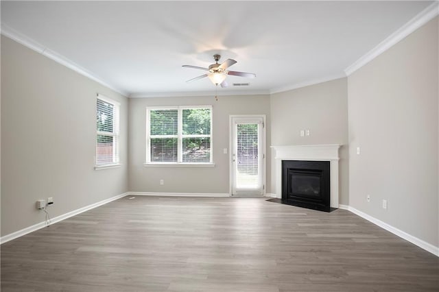 unfurnished living room with ceiling fan, wood finished floors, a fireplace with flush hearth, ornamental molding, and baseboards