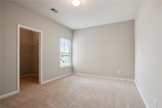 unfurnished bedroom featuring carpet flooring, a spacious closet, and baseboards