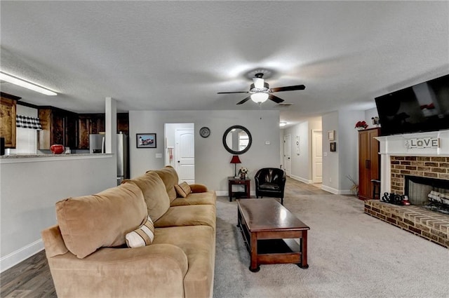 living room with carpet flooring, ceiling fan, a fireplace, and a textured ceiling