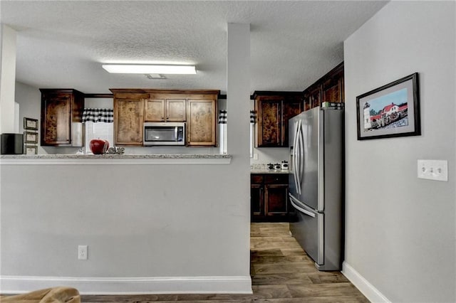 kitchen with dark hardwood / wood-style flooring, dark brown cabinetry, a textured ceiling, and appliances with stainless steel finishes