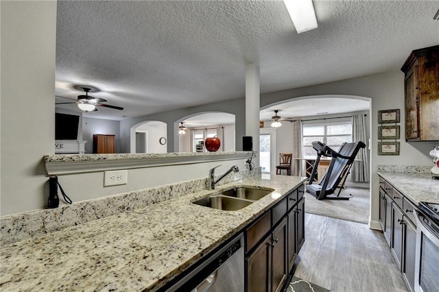 kitchen featuring a textured ceiling, dark brown cabinets, light stone counters, and sink