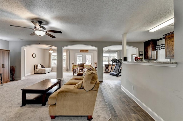 living room with french doors, a textured ceiling, light hardwood / wood-style flooring, and ceiling fan