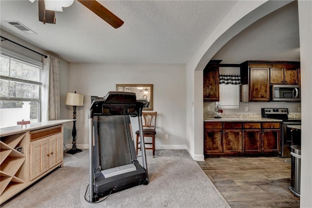 exercise area featuring hardwood / wood-style flooring, ceiling fan, and a textured ceiling