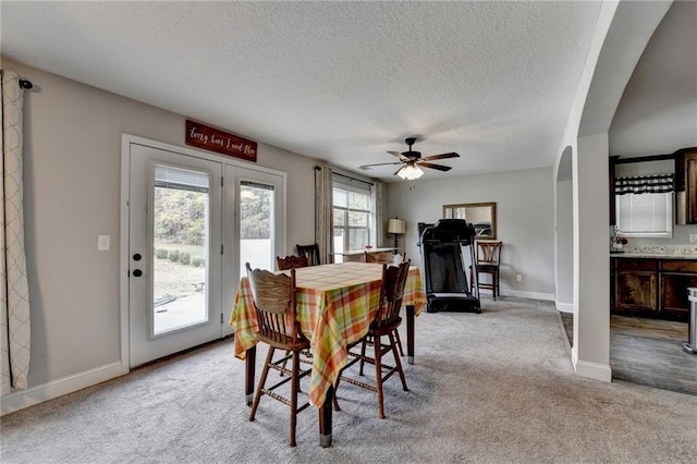 carpeted dining area with plenty of natural light, ceiling fan, and a textured ceiling