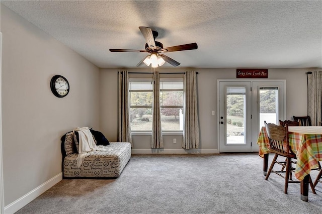 living area featuring carpet flooring, ceiling fan, and a textured ceiling