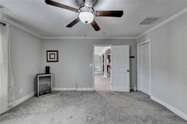 unfurnished living room with ceiling fan, light colored carpet, and crown molding