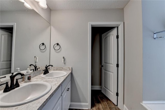 bathroom with a textured ceiling, vanity, and hardwood / wood-style flooring