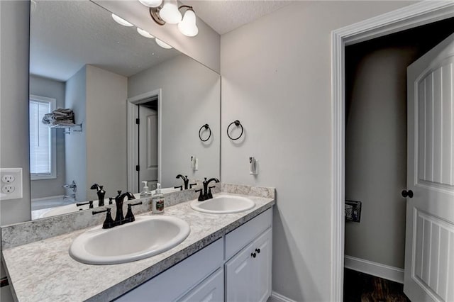 bathroom with hardwood / wood-style floors, vanity, and a textured ceiling