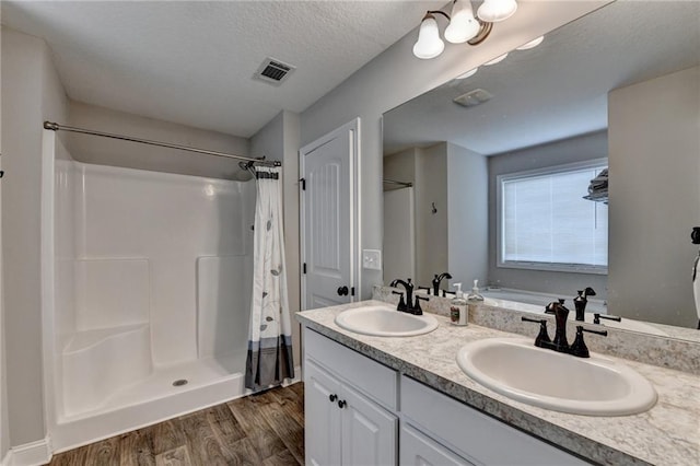 bathroom featuring hardwood / wood-style floors, vanity, a textured ceiling, and walk in shower