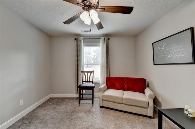 living area featuring ceiling fan, light colored carpet, and a textured ceiling