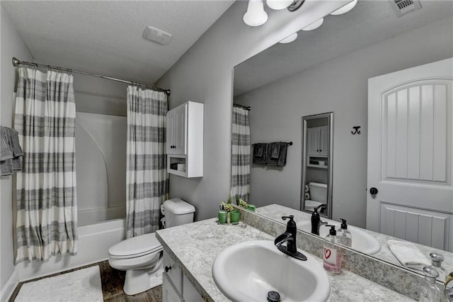 full bathroom featuring vanity, toilet, a textured ceiling, and shower / tub combo