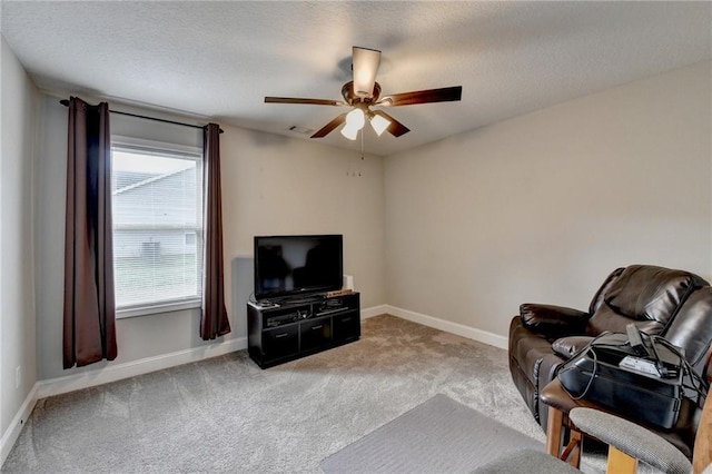 living area featuring ceiling fan, carpet, and a textured ceiling