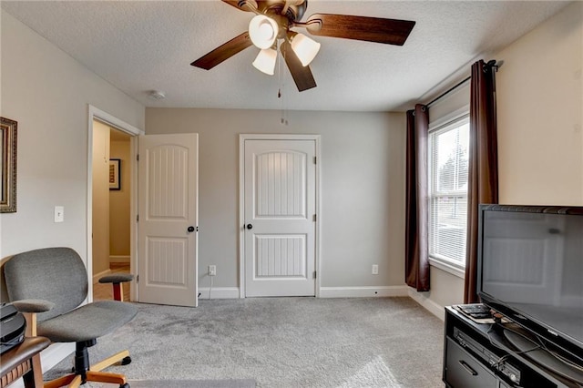 carpeted office featuring a textured ceiling and ceiling fan