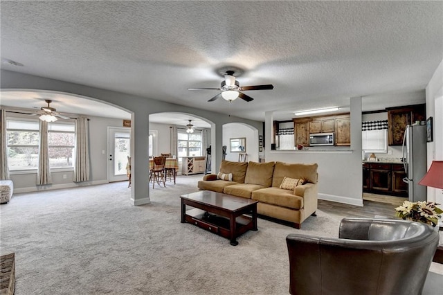 living room with ceiling fan, light colored carpet, and a textured ceiling