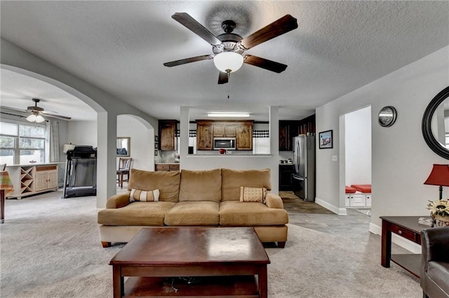 living room featuring ceiling fan, light colored carpet, and a textured ceiling