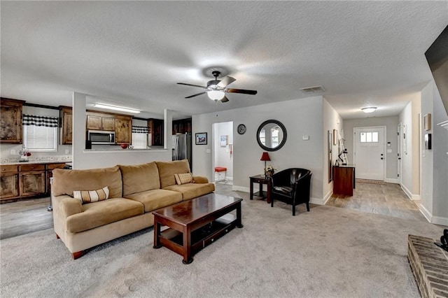 carpeted living room featuring ceiling fan and a textured ceiling