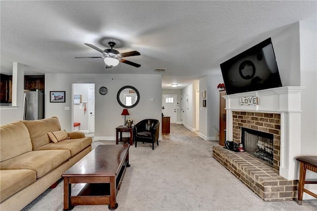 living room with a fireplace, a textured ceiling, light colored carpet, and ceiling fan