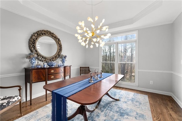 dining space with baseboards, a raised ceiling, wood finished floors, and ornamental molding