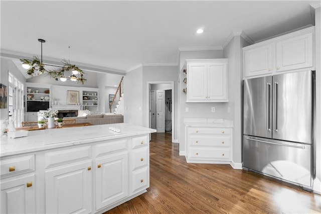 kitchen featuring white cabinets, open floor plan, wood finished floors, crown molding, and high end fridge