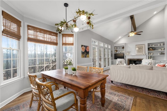 dining room with plenty of natural light, a fireplace, vaulted ceiling, and wood finished floors