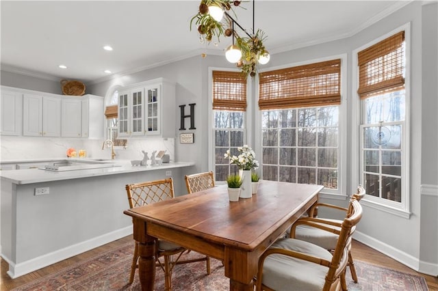 dining space featuring baseboards, wood finished floors, and crown molding