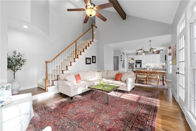 living area featuring high vaulted ceiling, wood finished floors, baseboards, stairway, and beamed ceiling