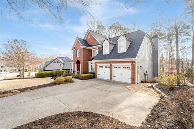 view of front of house featuring brick siding, a chimney, a shingled roof, a garage, and driveway