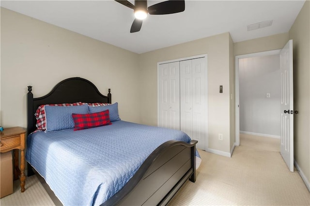 bedroom with baseboards, visible vents, light colored carpet, ceiling fan, and a closet